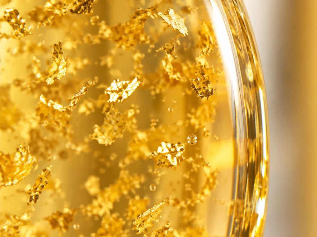 An extreme macro photograph looking through the curved glass wall of the exact Gold Foil bottle, foc